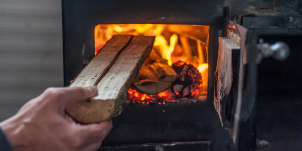 Man putting log to wood burning stove. Close up