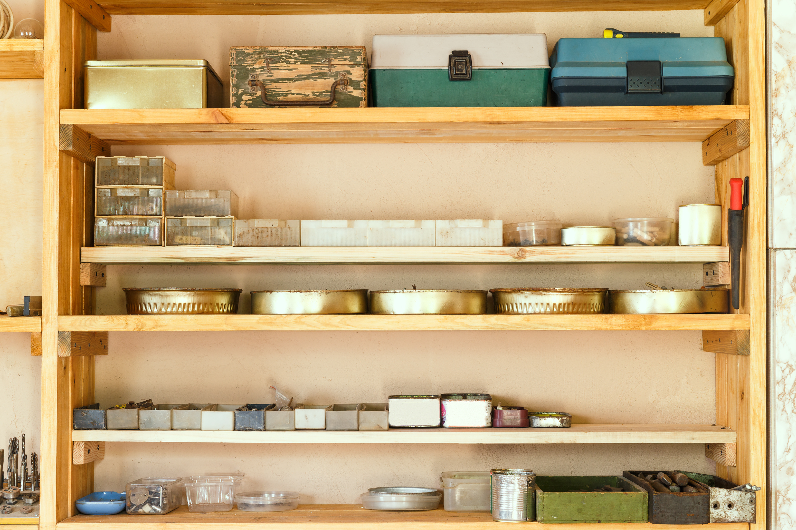 Wooden shelving units with different furniture in custom workroom. Boxes with various accessories and tools are placed on the shelves.