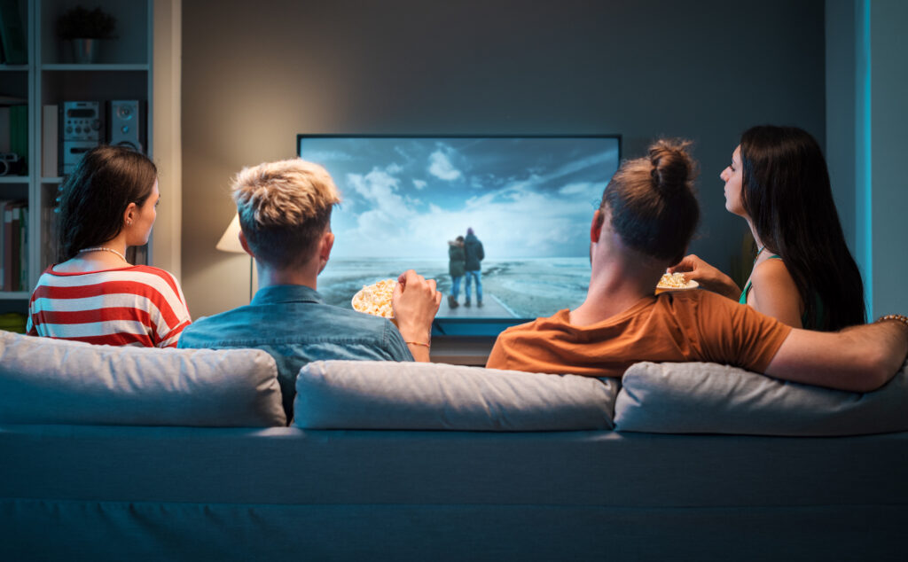 Group of friends sitting on the couch at home and watching movies together