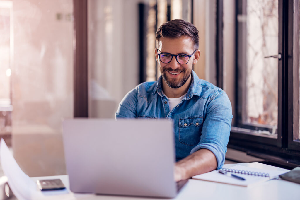 Smiling businessman sitting in office and working on laptop. High quality photo