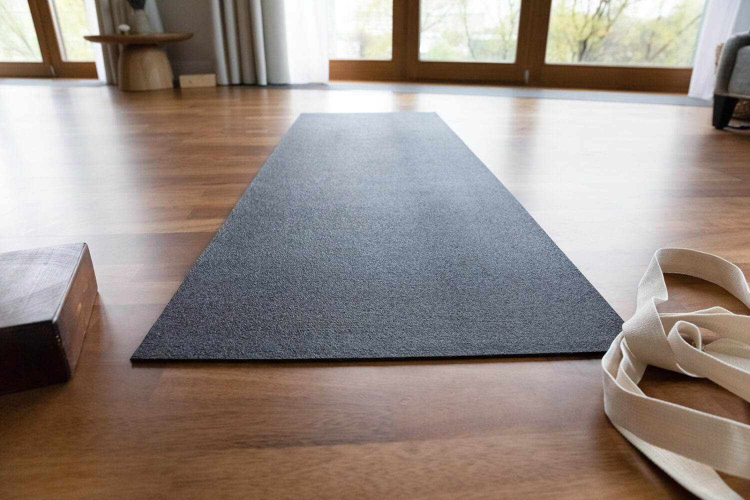 Dark grey yoga mat and strap in empty room