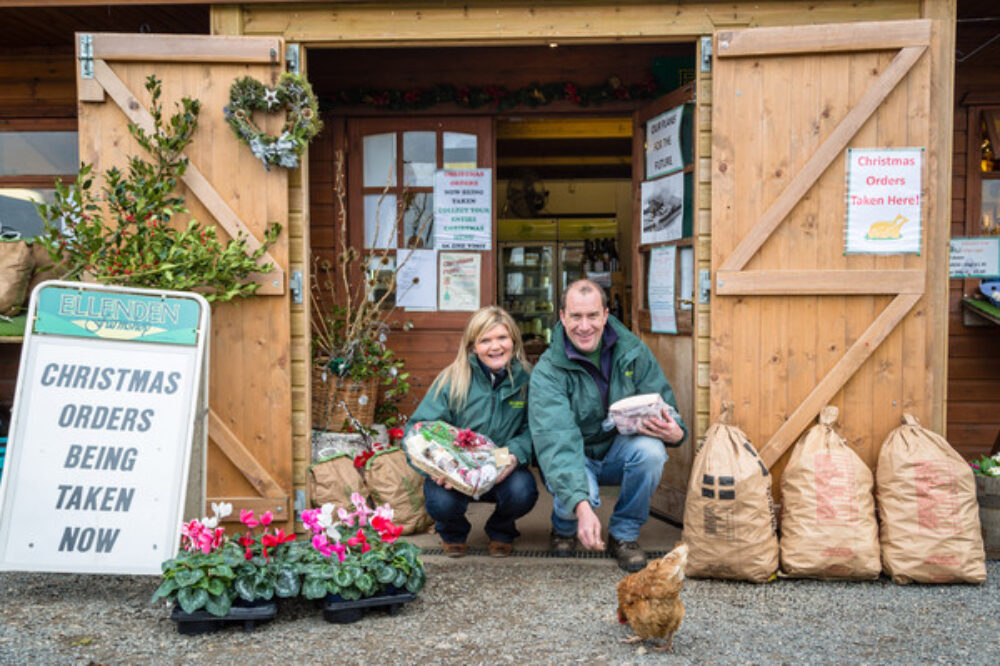 Front of timber farm shop with owners feeding chicken