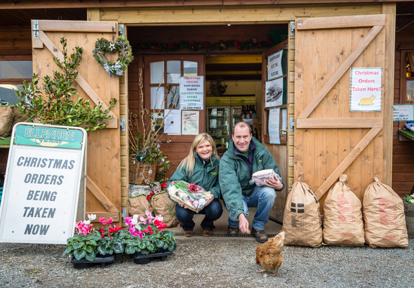 Front of timber farm shop with owners feeding chicken