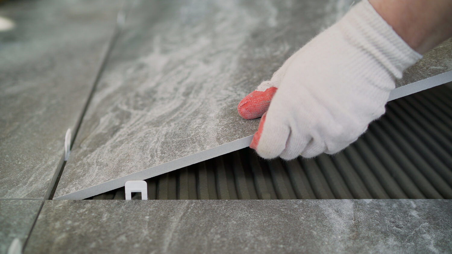 A worker puts a large tile on the floor