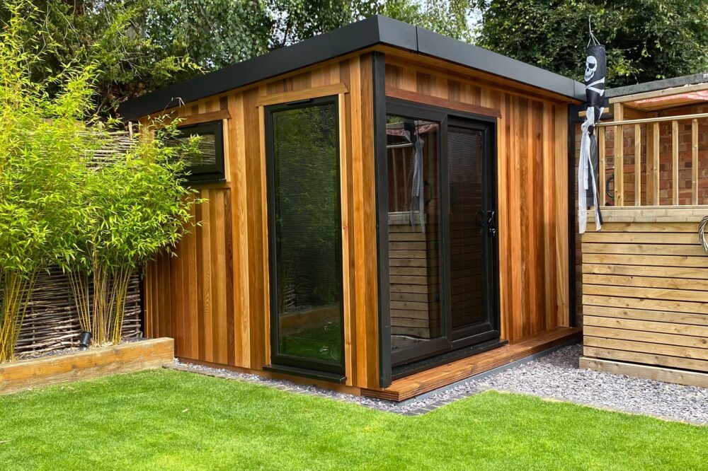 Modern timber garden room with black framed doors and windows in a landscaped garden in Warwickshire