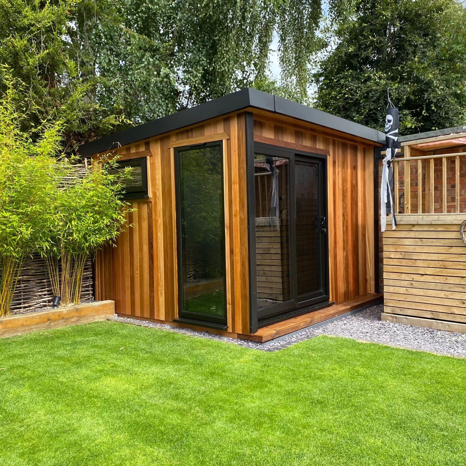 Modern timber garden room with black framed doors and windows in a landscaped garden in Warwickshire