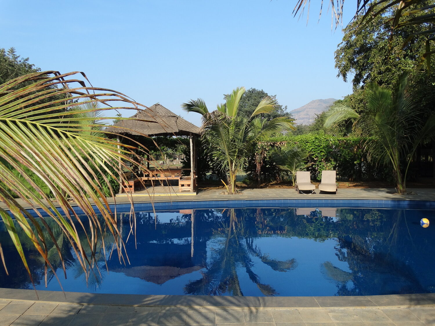 reflection of the gazebo setting & forest in the swimming pool at the feet of the mountain